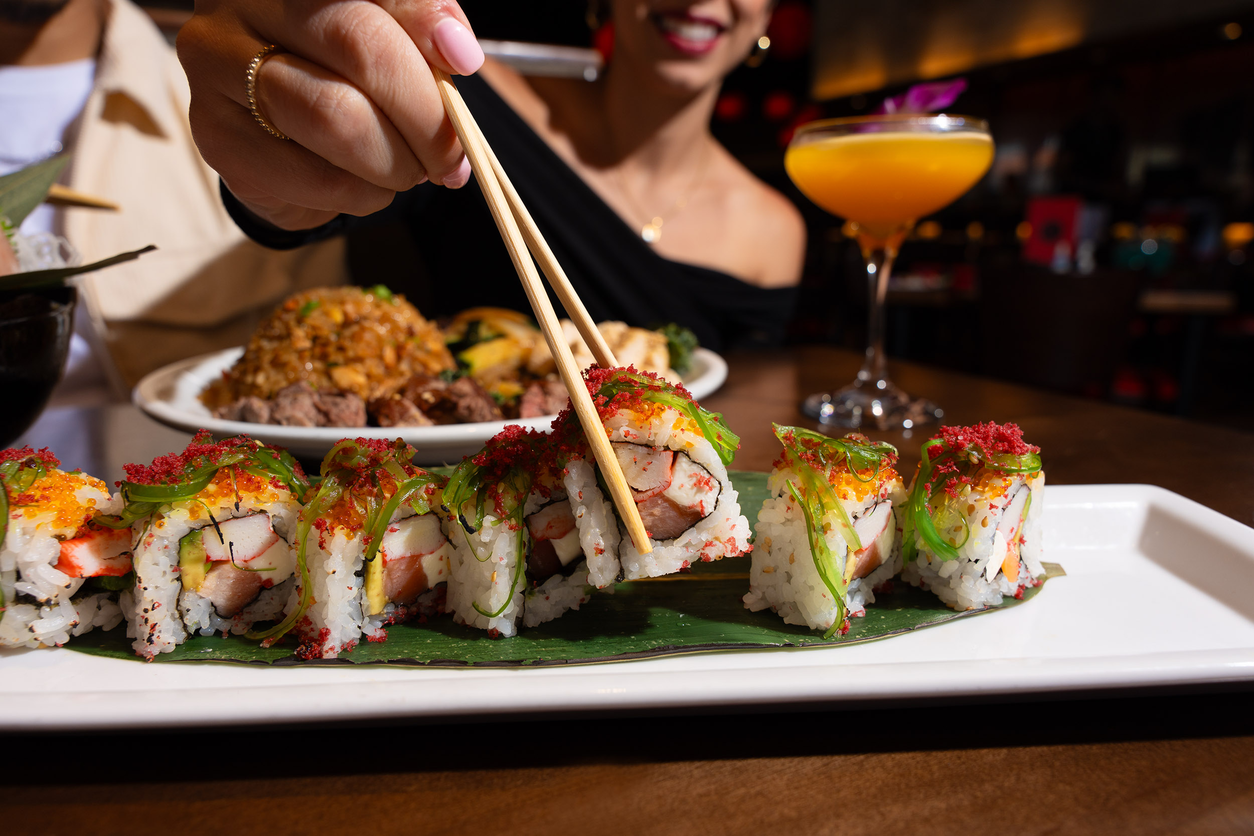 A couple enjoys fresh sushi, signature cocktails, and festive holiday vibes at RA Sushi. Celebrate the season with handcrafted rolls, vibrant flavors, and the perfect date-night atmosphere.
